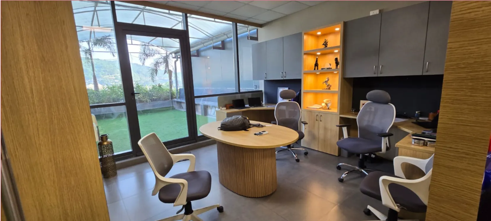 The Essentient studio in Navi Mumbai — a meeting table and desks beside a window onto the garden.